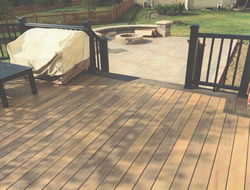 Wooden deck with stairs leading to pave patio with fire pit.